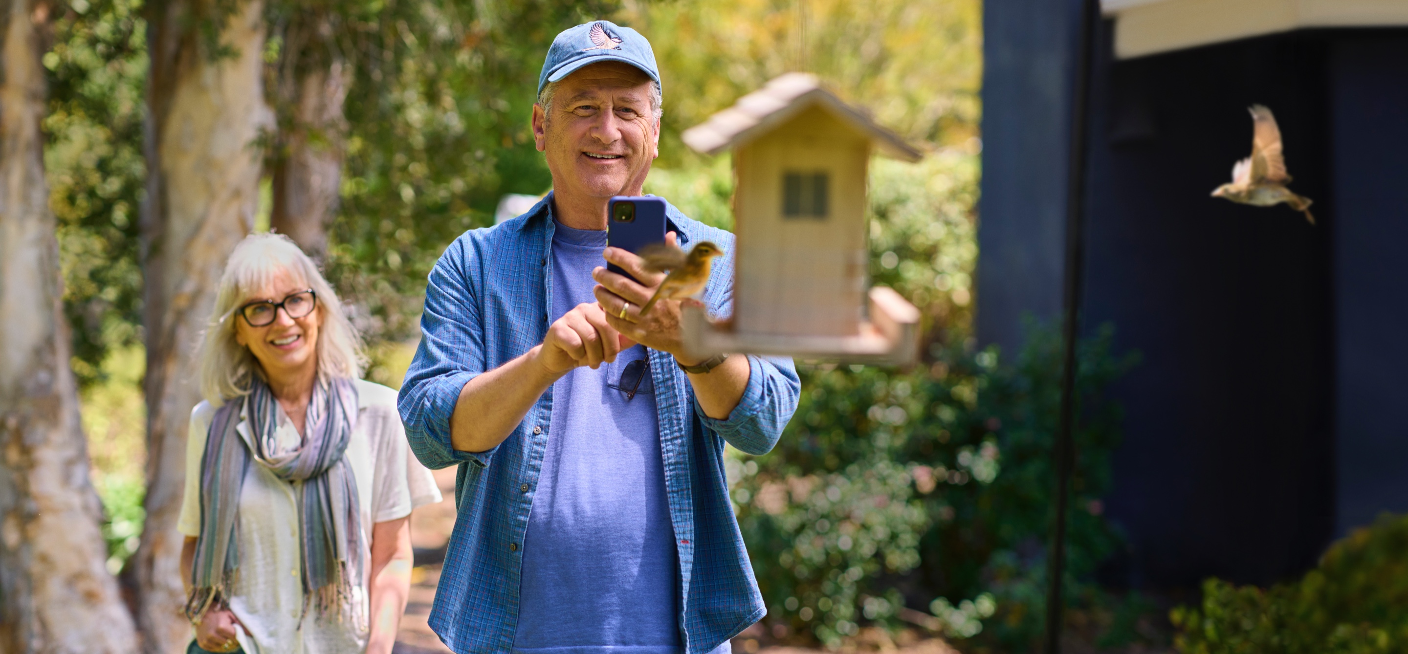 man taking a photo of a birdhouse with his partner